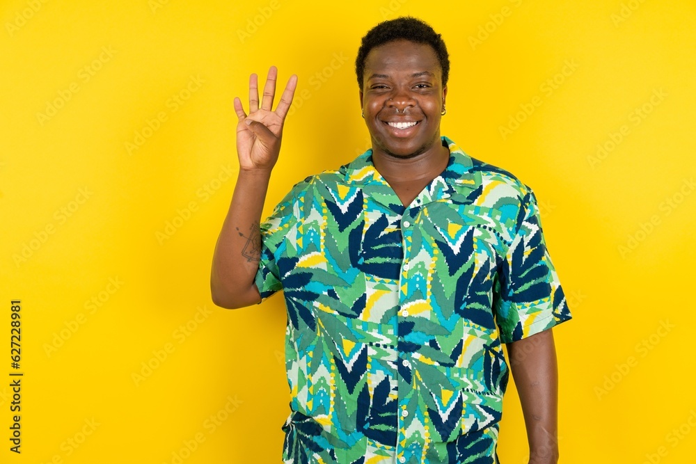 Young latin man wearing hawaiian shirt over yellow background showing and pointing up with fingers number four while smiling confident and happy. Young latin man wearing hawaiian shirt over yellow background showing and pointing up with fingers number four while smiling confident and happy.