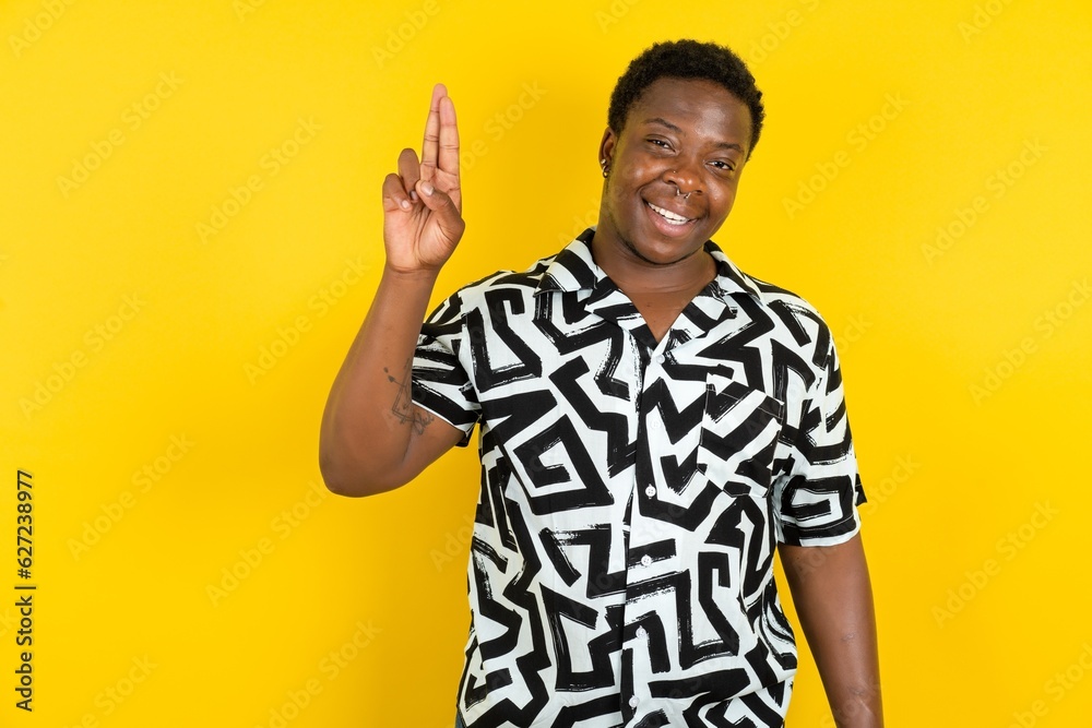 Young latin man wearing printed shirt over yellow background pointing up with fingers number ten in Chinese sign language Shi