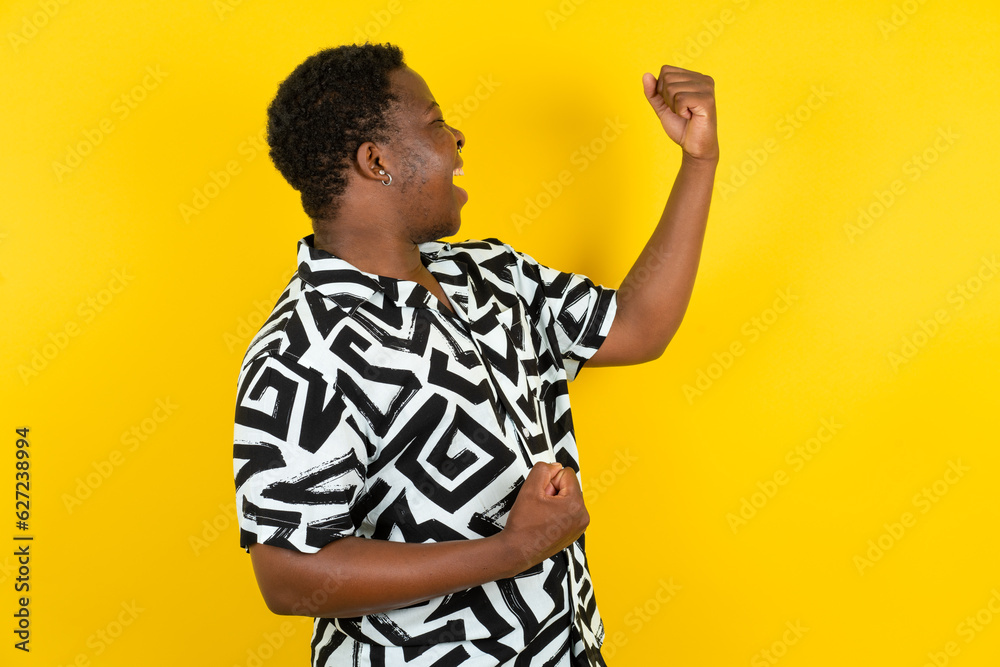 Profile photo of excited Young latin man wearing printed shirt over yellow background good mood raise fists screaming rejoicing overjoyed basketball sports fan supporter Profile photo of excited Young latin man wearing printed shirt over yellow background good mood raise fists screaming rejoicing overjoyed basketball sports fan supporter