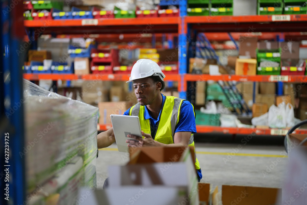 Worker working in large warehouse holding paper chart check list checking the material compare with the boxes wrapped with plastic keep on wooden pallet ready to ship to customer