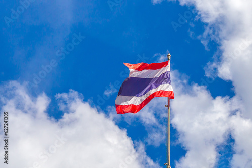 Photo of waving Thai flag of Thailand with blue sky and white clouds background.