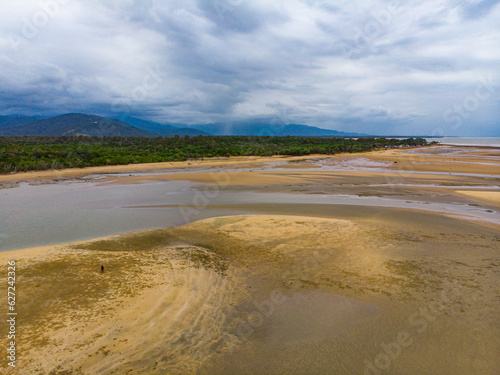 lonely girl walking on the sandy beach near the mouth of river in balgal beach, north queensland, australia © Jakub
