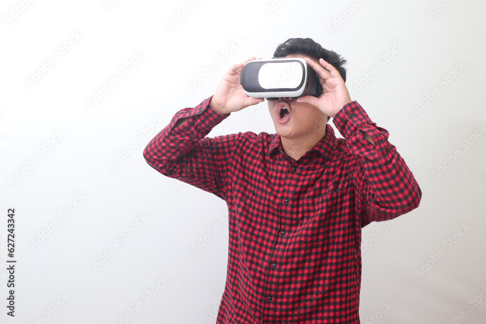 Portrait of Asian man in red plaid shirt using Virtual Reality (VR) glasses and looking up. Isolated image with copy space on white background Portrait of Asian man in red plaid shirt using Virtual Reality (VR) glasses and looking up. Isolated image with copy space on white background