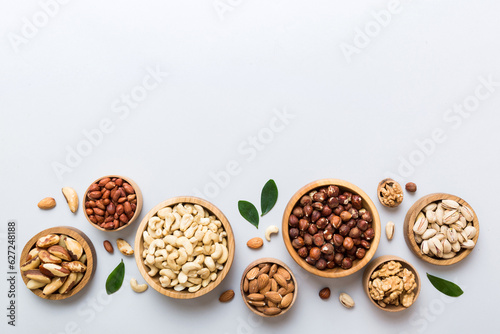 mixed nuts in wooden bowl. Mix of various nuts on colored background. pistachios, cashews, walnuts, hazelnuts, peanuts and brazil nuts