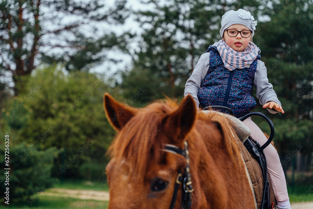 Foto de Little girl riding on a horseback. The girl is sitting on a ...