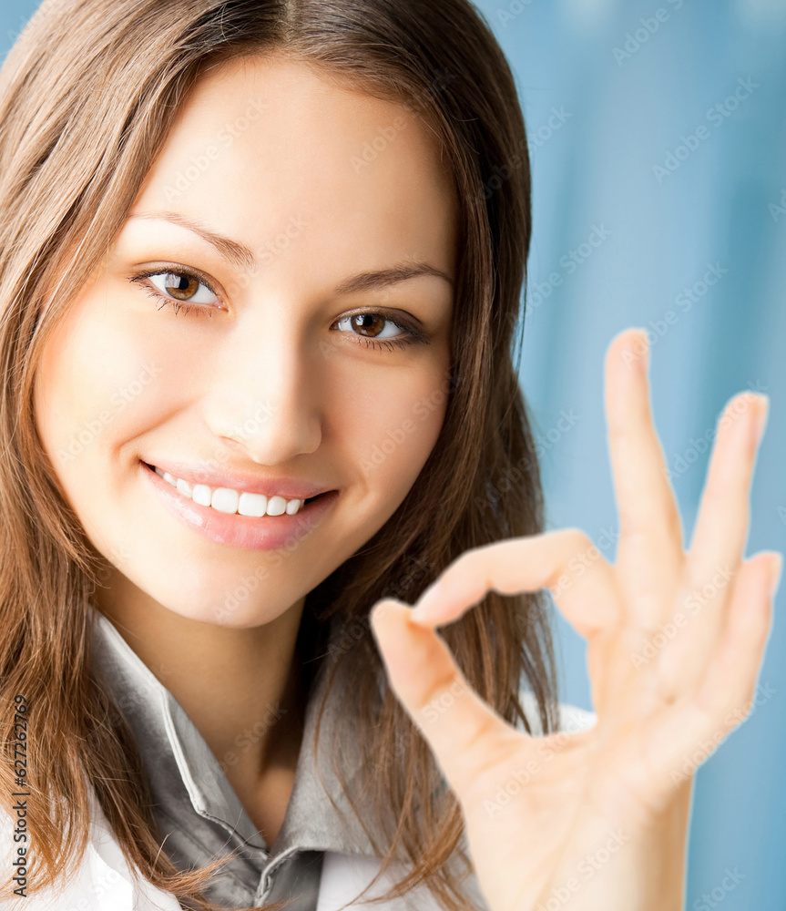 Happy smiling cheerful young female doctor with okay gesture, at office Happy smiling cheerful young female doctor with okay gesture, at office