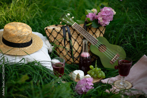 Picnic in the forest on green grass. Wine and fruit on the grass. Next to the flowers