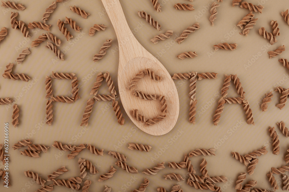 Gluten free flax pasta scattered on brown surface, top view. Design