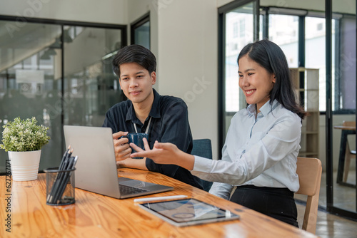 Two Asian colleagues are discussing the work. The businessman is laptop and tablet in office