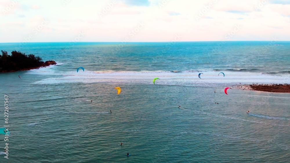 Approaching frame of kiteboarding in ocean. Aerial view, kitesurfing freestyle at hot sunny day. Active extreme water sport in tropical nature. Amazing kitesurfing or windsurfing on blue sea water.