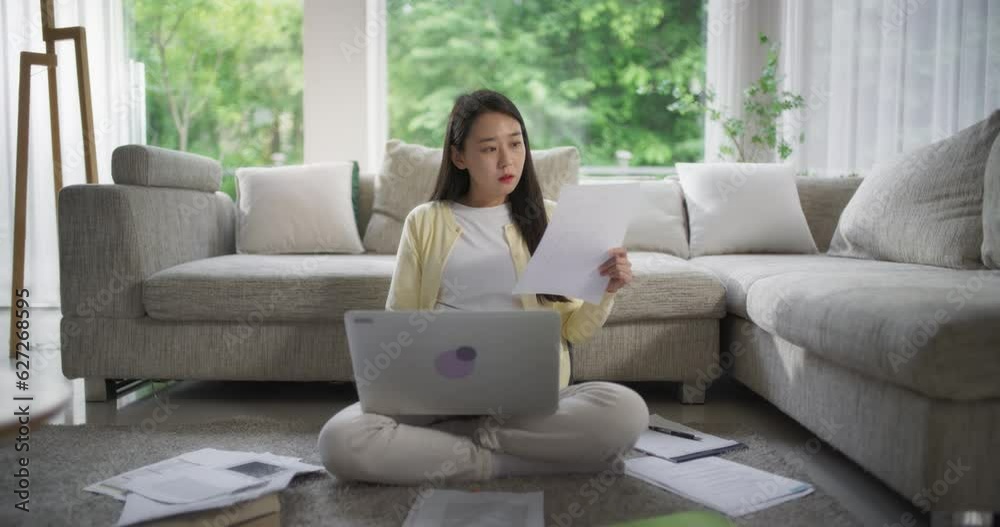 거실 바닥에 앉아 노트북으로 원격 팀과 협업하는 한국 여성 거실 바닥에 앉아 노트북으로 원격 팀과 협업하는 한국 여성