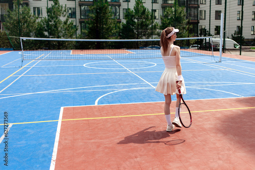 girl tennis player in white uniform holding racket on tennis court, female athlete playing tennis outdoors © Богдан Маліцький