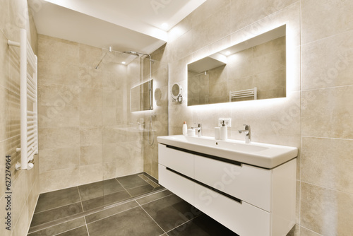 a modern bathroom with black and white floor tiles on the walls  sink  mirror and shower stall in the corner