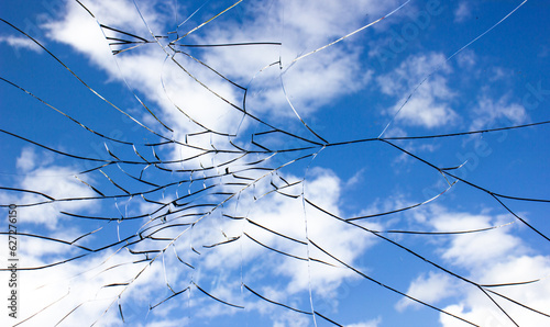 Cracks on glass.Cracked glass and sky. Damaged by impact, explosion glass.