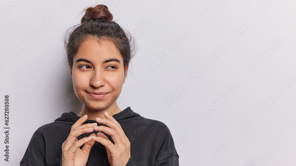 Cunning young woman with mischievous smirk and fingers steepled reveals devious idea brewing in her mind dressed in casual black hoodie isolated over white background copy space for your advertisement Cunning young woman with mischievous smirk and fingers steepled reveals devious idea brewing in her mind dressed in casual black hoodie isolated over white background copy space for your advertisement