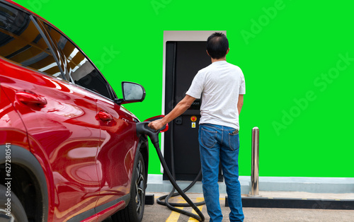 Man hold electric charging car at a charging station.Electric vehicle recharge battery at a public charging station in the city area. EV car attached with electric charger for eco-friendly idea.