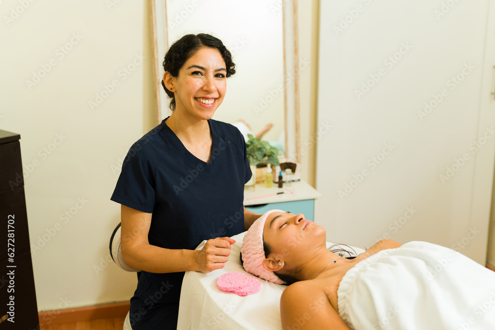 Fototapeta premium Cheerful therapist giving a skin care facial treatment