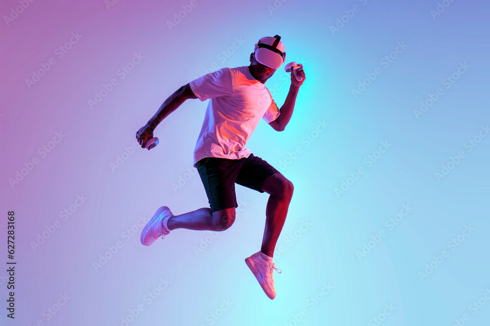 african american athletic man quickly runs and jumps in virtual reality glasses in neon lighting