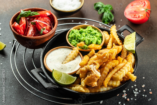 Fotografia British traditional fish and potato chips served with mashed peas, vegetable salad, tartar sauce, Food recipe background