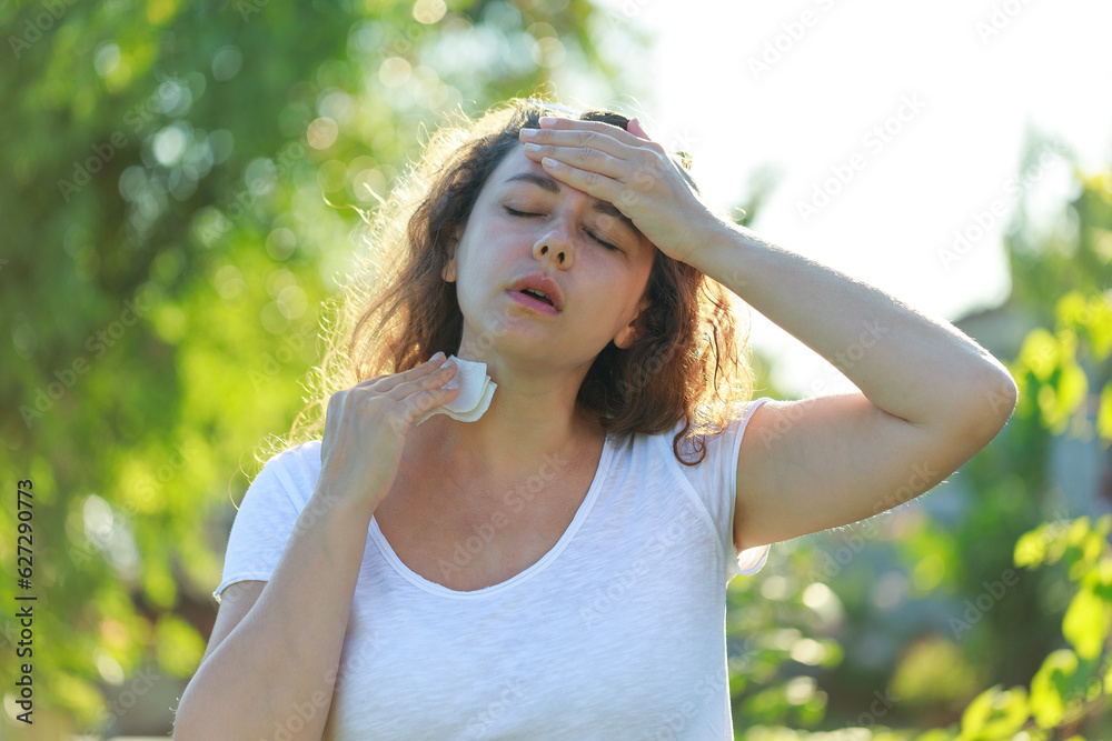 Young woman having hot flash and sweating in a warm summer day Young woman having hot flash and sweating in a warm summer day