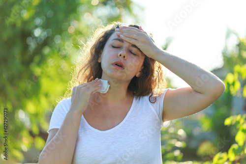 Young woman having hot flash and sweating in a warm summer day