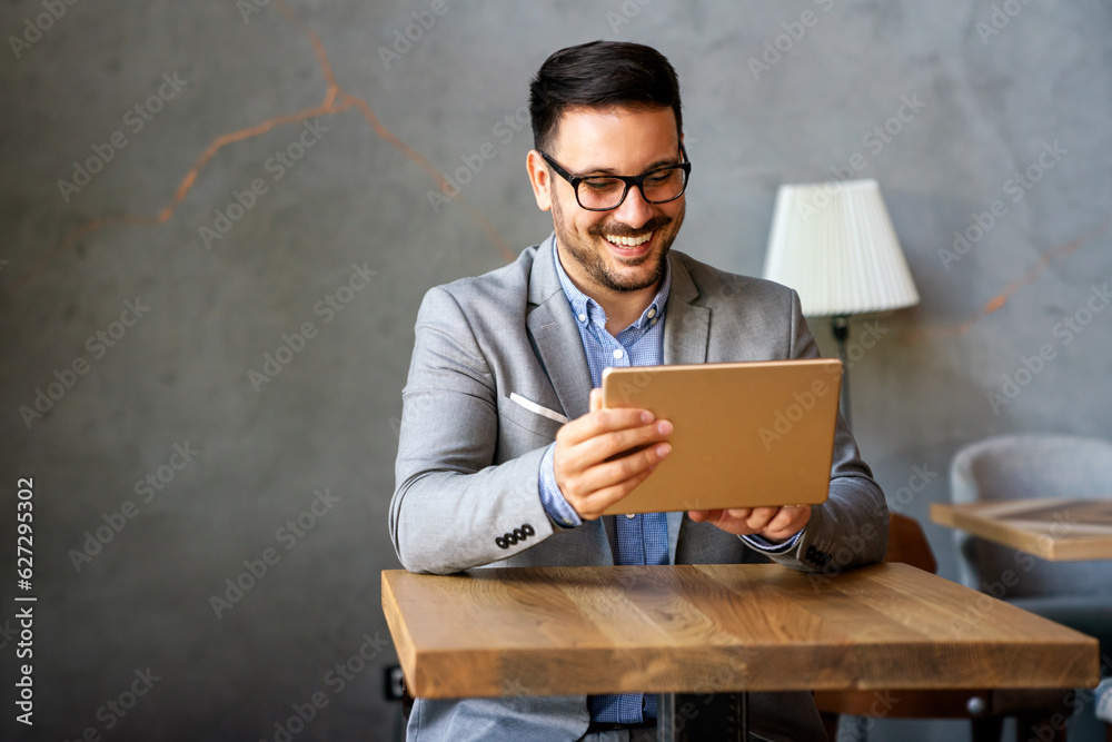 Portrait of young successful businessman with digital device working in corporate business office