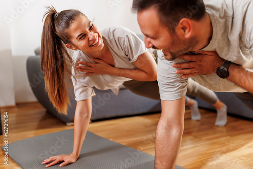 Couple doing home workout holding plank pose