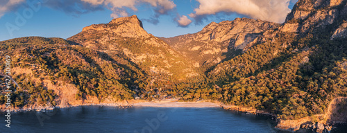 Aerial view of the mesmerizing beauty of the Lycian Way on the sea coast in Turkey during sunset. Scene unfolds with majestic mountains bathed in the warm hues of the setting sun.
