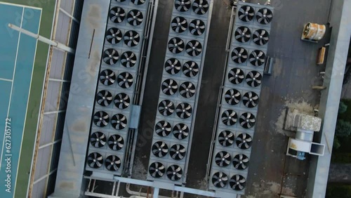 Three rows of outdoor air conditioner chiller fan coil compressors on the roof of a building. View from a drone