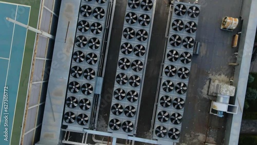 Three rows of outdoor air conditioner chiller fan coil compressors on the roof of a building. View from a drone photo