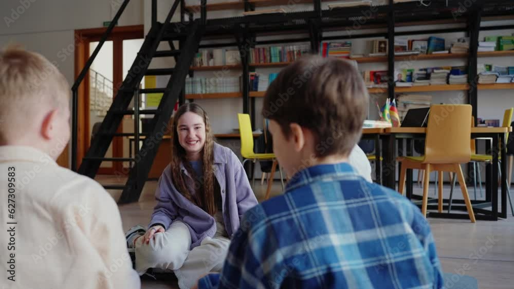 Cheerful kids high-five each other sitting in circle on floor in library Cheerful kids high-five each other sitting in circle on floor in library