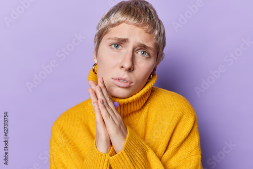 Obraz na plátně Headshot of blonde short haired young woman keeps hands in praying gesture with