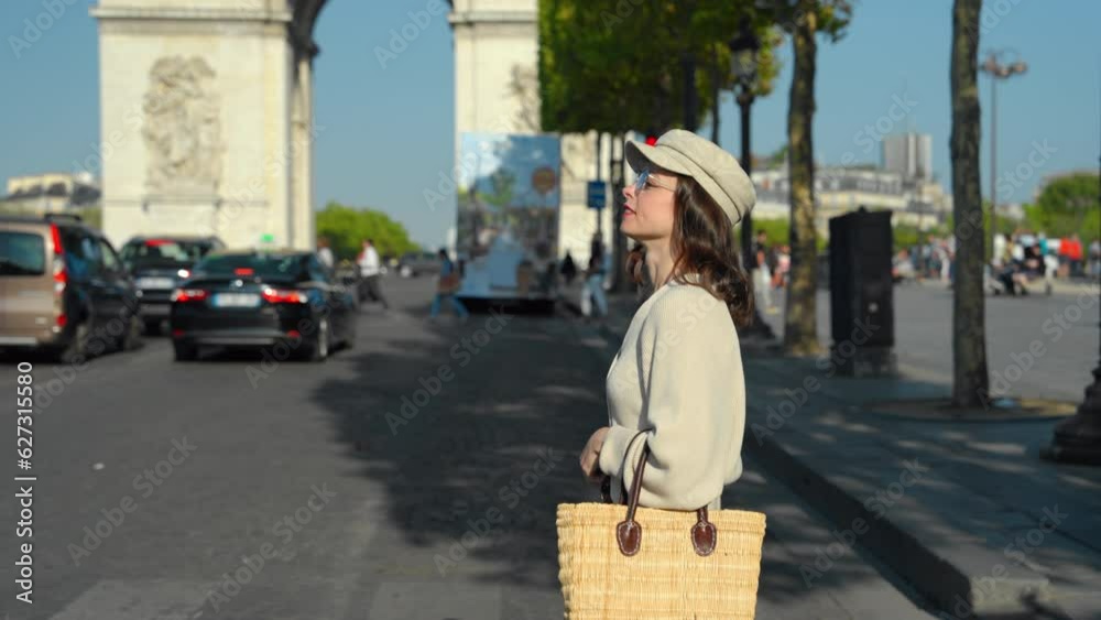Happy girl walking in the sunny city against the backdrop of the Arc de Triomphe