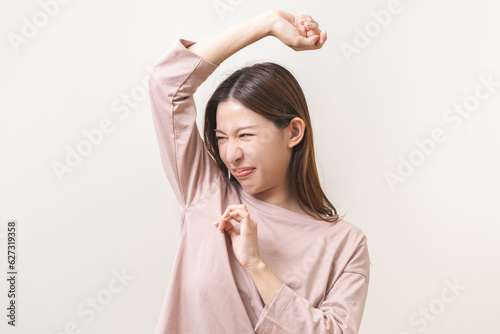 Bad smelling, deodorant asian young woman smell stink, breathing nose on armpit with underarm, smelly shirt dirty stinky laundry, disgusting from clothes after washed. Medical health, skin body care.