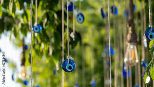 Schilderij op canvas Blue evil eye beads hanging with a rope from a tree branch