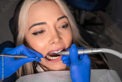 Dentist treats the teeth of a young woman. Portrait of a beautiful young woman in the process of dental treatment in a dentist's chair. Modern technologies in dentistry