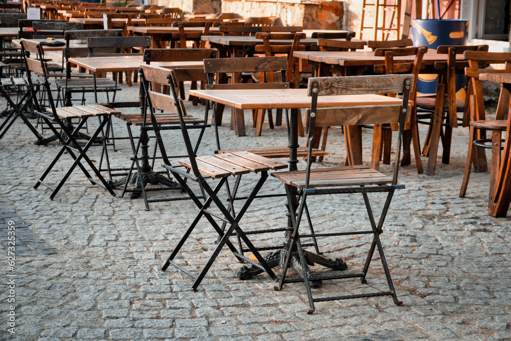 wooden folding iron chairs and tables placed on the street in front of a cafe