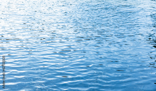 Shiny water surface with reflections of blue sky, abstract photo