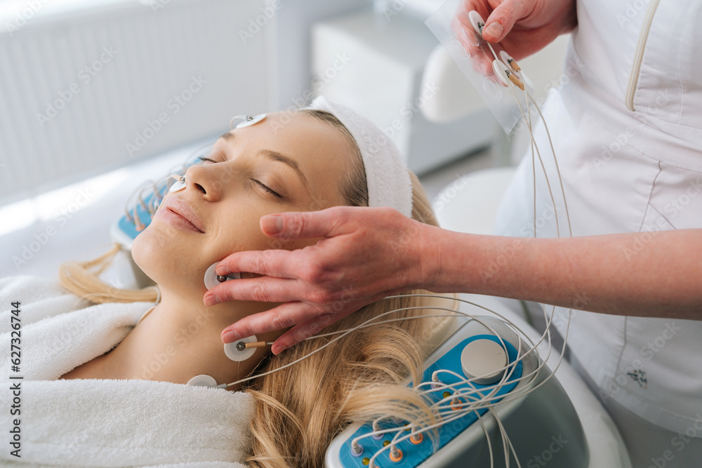Close up cropped shot of hardware electro myostimulation procedure at beauty spa salon, cosmetologist apply equipment on patient relaxed face. Concept of non-surgery cosmetology, professional skincare
