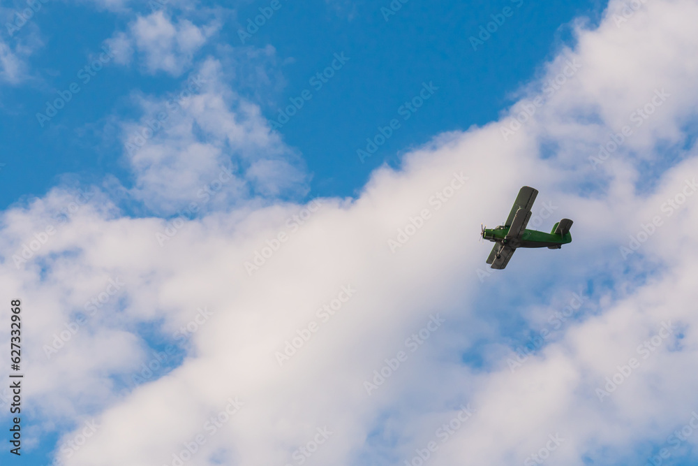 Fototapeta premium Green biplane, retro airplane flying in blue sky at Air Show. Performance, extreme, aerobatic, sport and aircraft concept