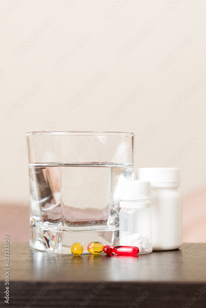 Attractive sick pregnant woman is lying in sofa. Taking pills from colds