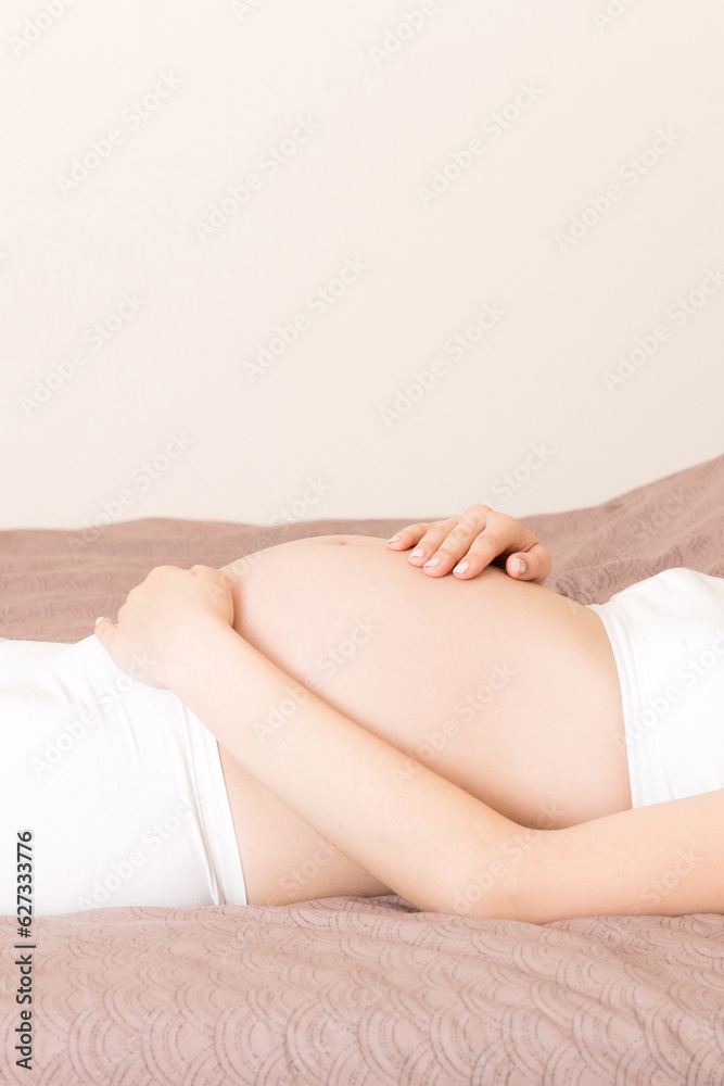 Young pretty pregnant woman, in pain, sitting on bed in bedroom, preparing to give a birth Young pretty pregnant woman, in pain, sitting on bed in bedroom, preparing to give a birth