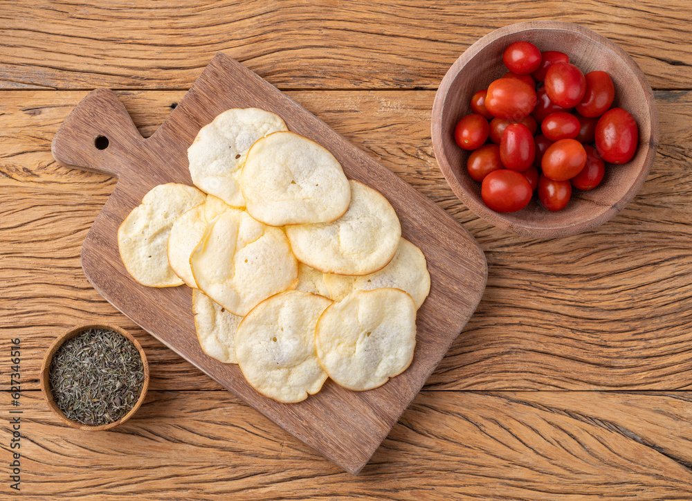 Smoked provolone cheese chips in a bowl with cherry tomatoes and oregano over wooden table