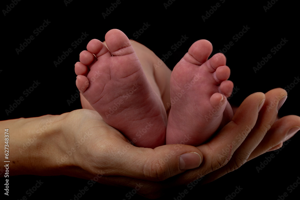 Hand of a mother holding tiny baby feet Hand of a mother holding tiny baby feet