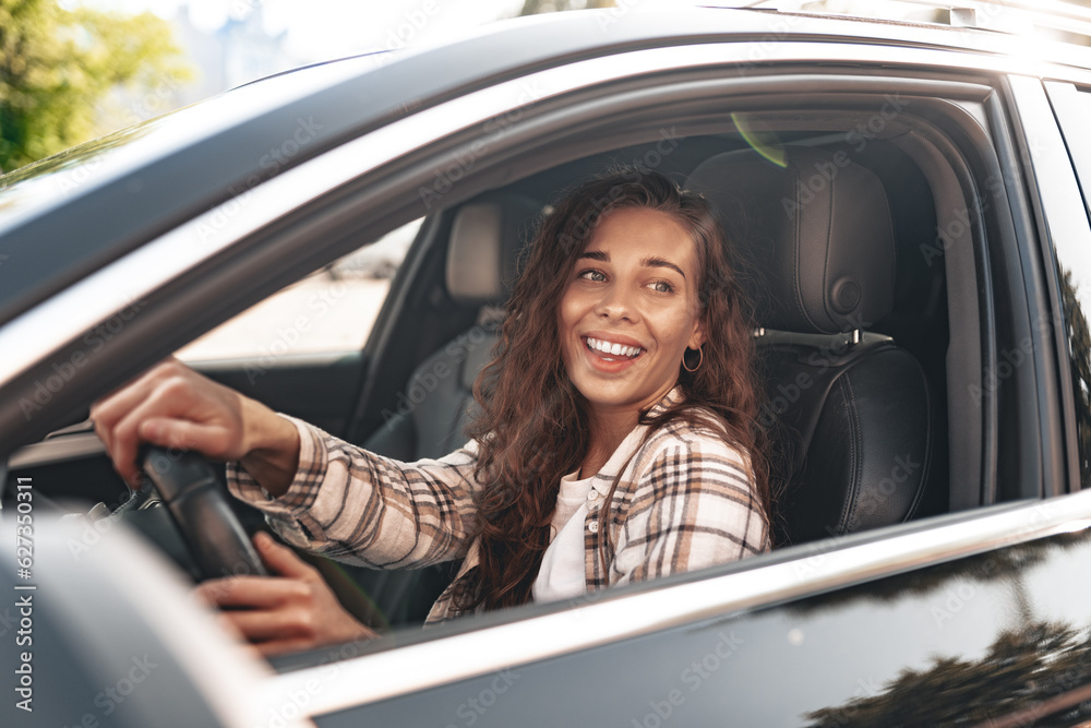 Young smiling woman driving a car in the city
