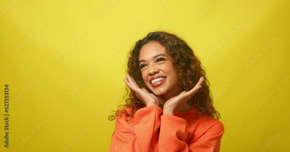 Beautiful multiracial woman cups hands under chin in cute pose, yellow studio Beautiful multiracial woman cups hands under chin in cute pose, yellow studio
