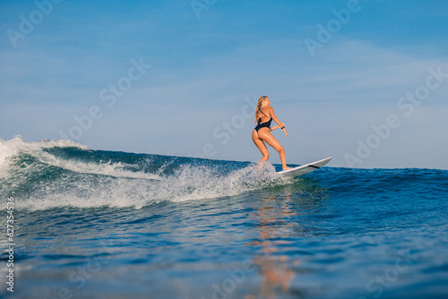 Photography Surfer woman riding on ocean wave on surfboard