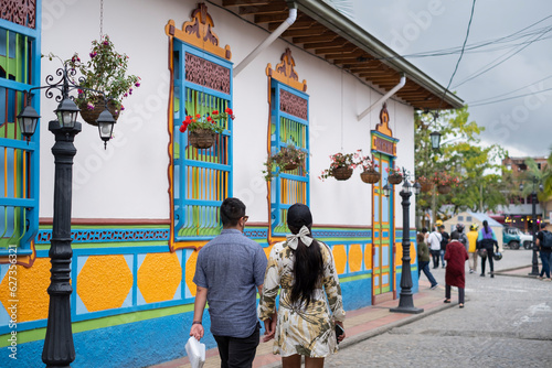 Couple walking at narrow street of Guatape with the famous colorful painted facades of the buildings.Selective focus, blurred background.