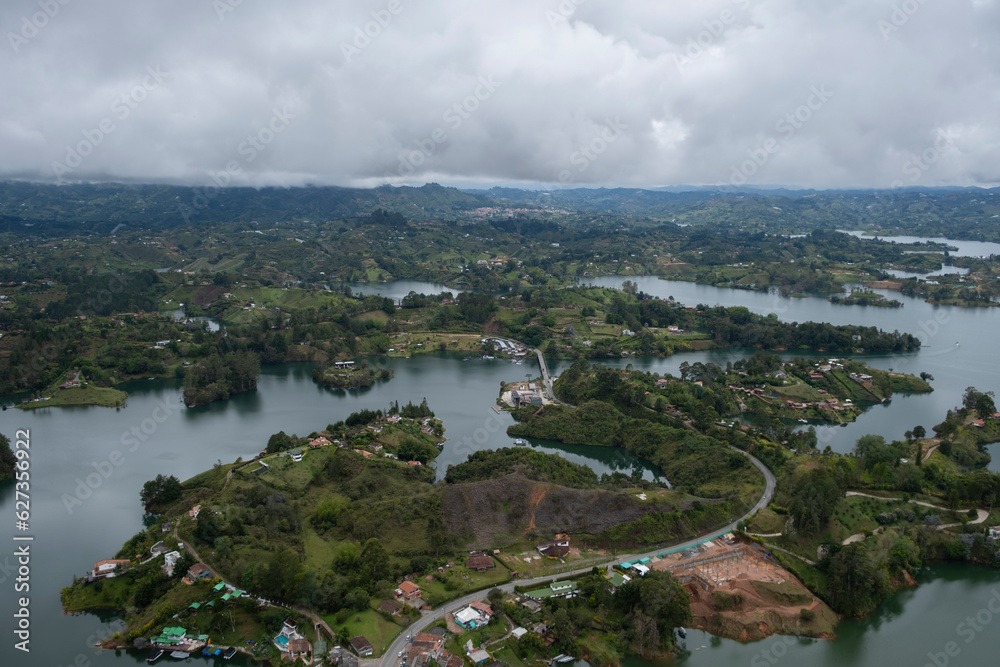 Aerial panoramic view of the hydroelectric reservoir, lakes, mountains and many small islands of Guatape covered with low clouds and fog on a rainy day with low visibility, near Medellin, Colombia.