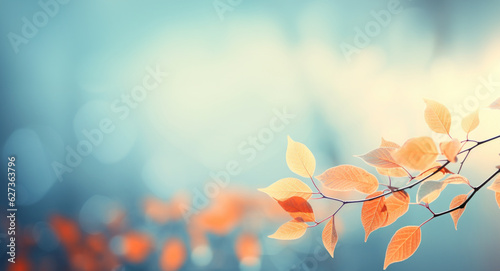 Abstract autumn nature background, with leaves on a branch, glowing sun and warm seasonal colors